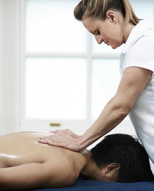A client lying face down on a physio table whilst a Ten Health & Fitness physiotherapist treats their upper back.