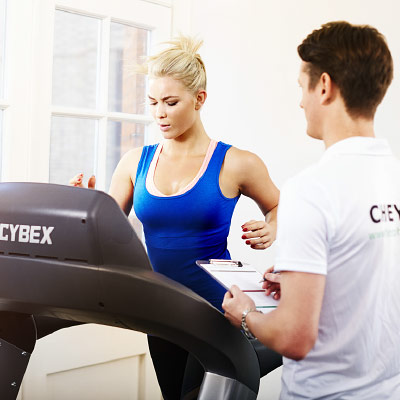 A woman running on a treadmill, being observed by a trained physiotherapist as part of a physiotherapy assessment at Ten Health & Fitness.