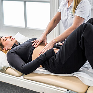 A client having their abdomen examined by a Ten pelvic health physiotherapy specialist.